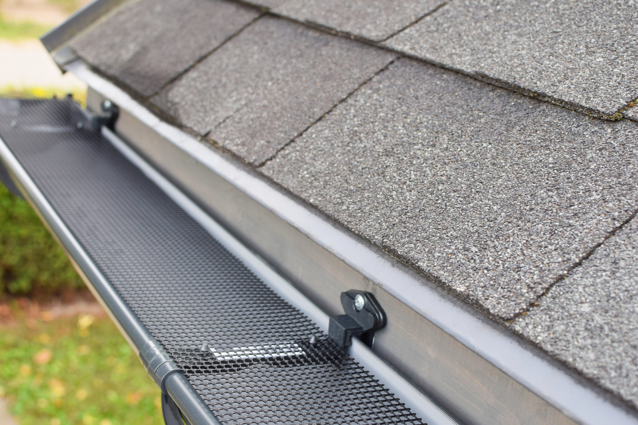 Plastic guard over new dark grey plastic rain gutter on asphalt